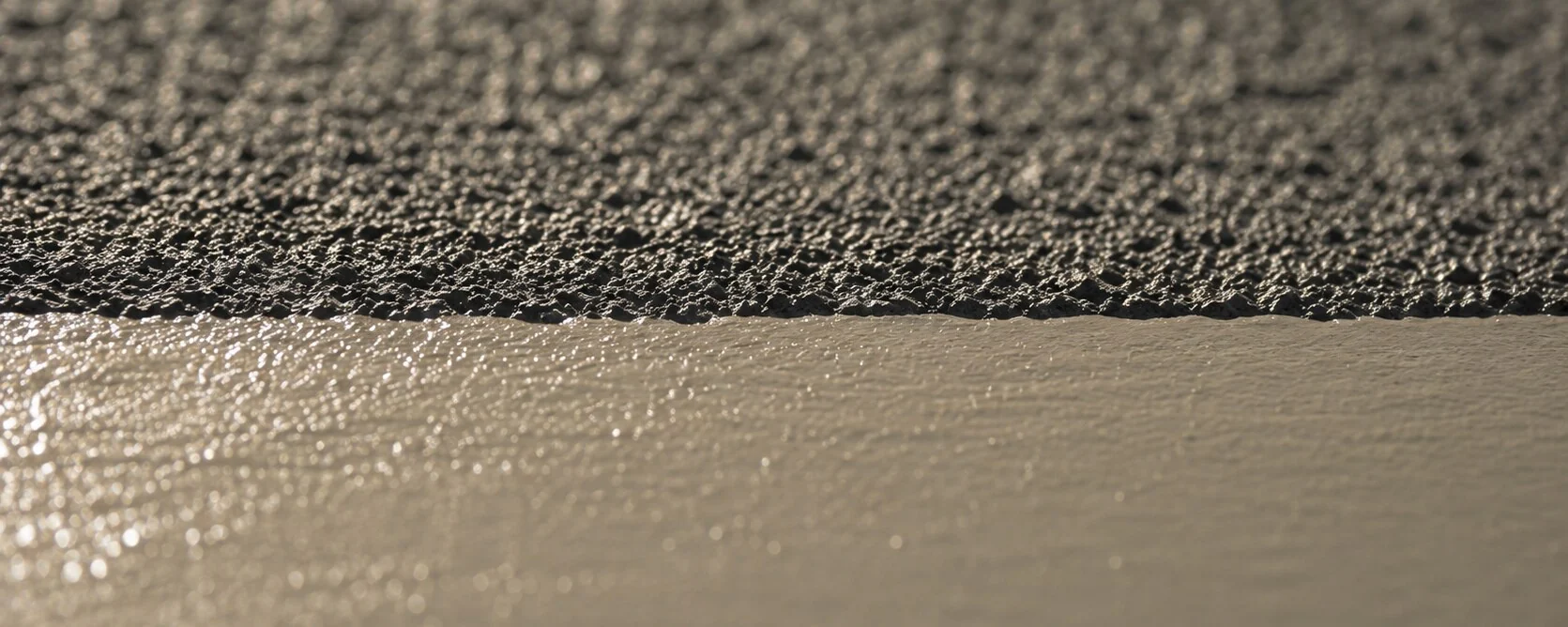 Close-up of a steel surface: blast-cleaned steel with its anchor profile on the left, freshly applied coating on the right