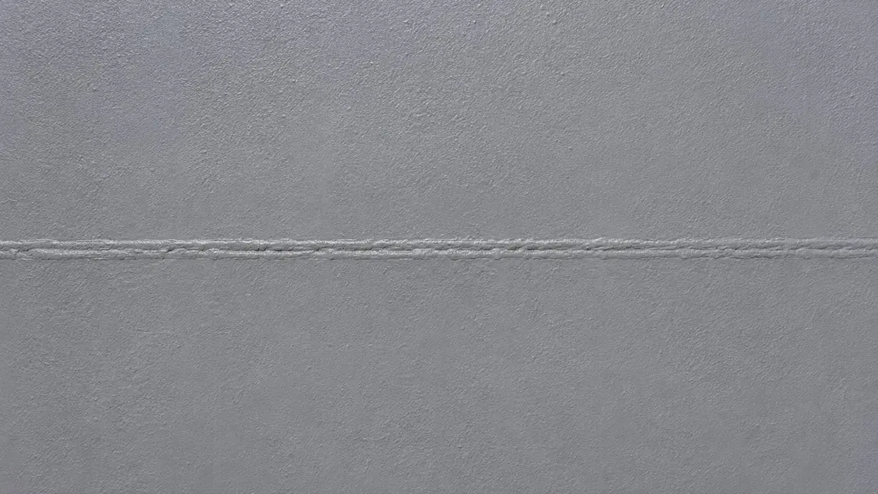 The same steel surface after reinstatement: an even, continuous grey coating with the weld seam fully protected