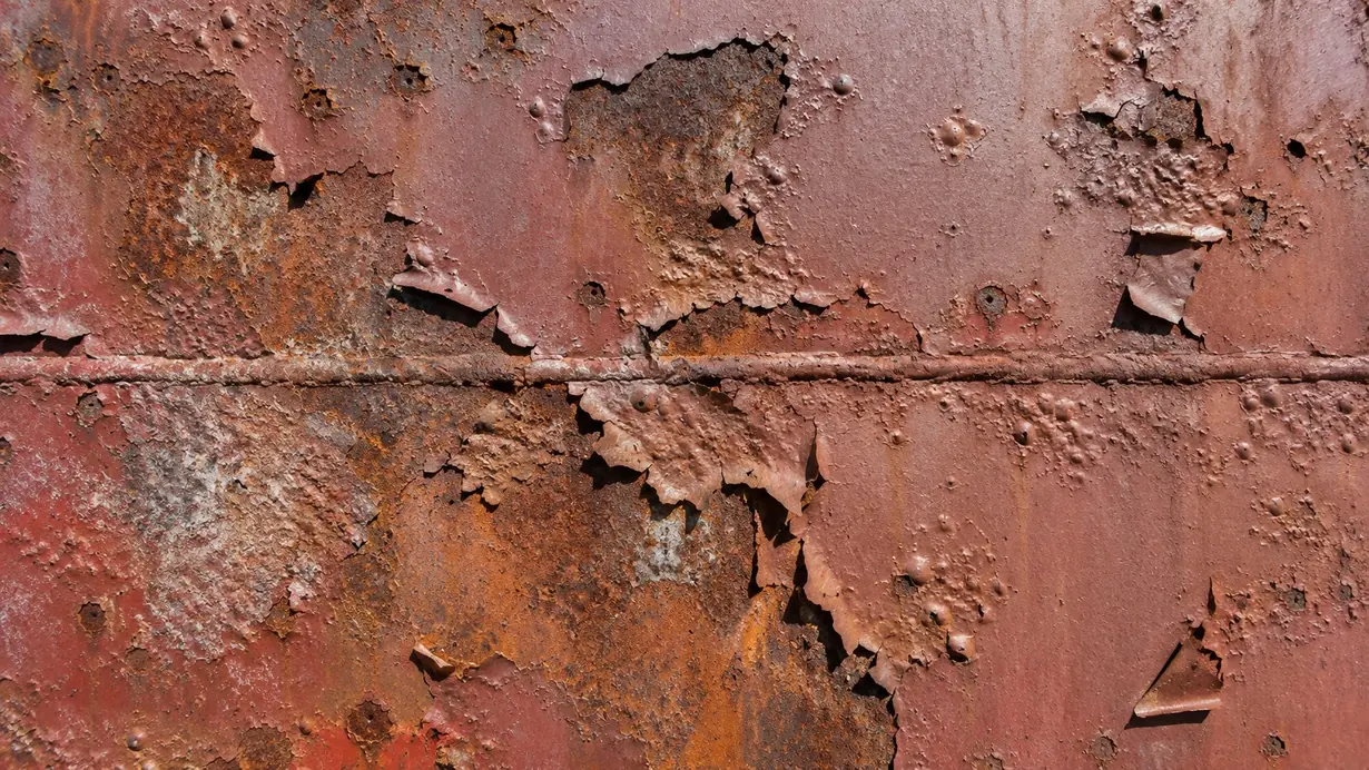 Steel surface with a deteriorated coating: flaking, detachment of the paint film and widespread corrosion around a horizontal weld seam