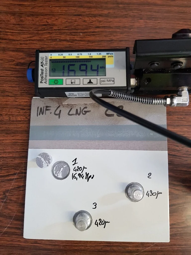 Pull-off adhesion tester resting beside the three dollies detached at the end of the test