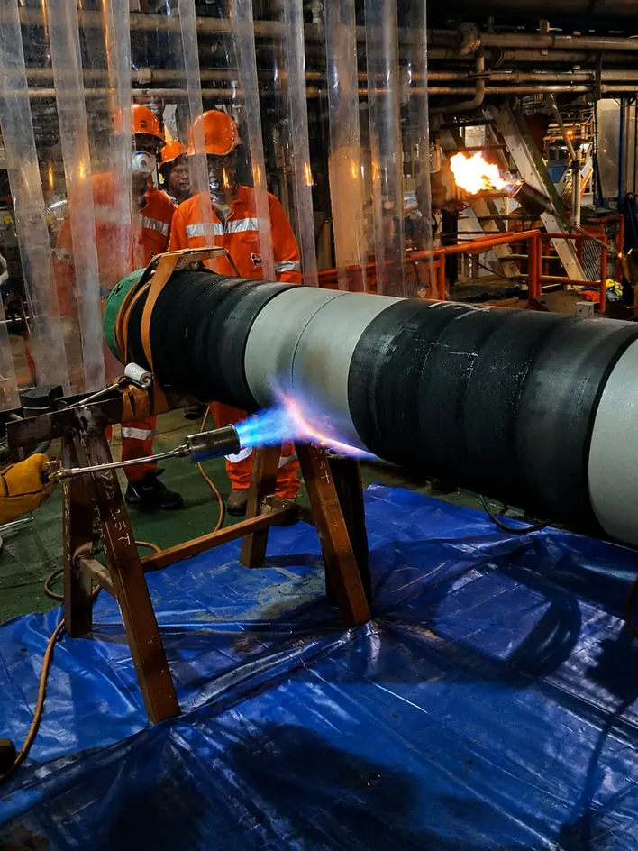 Work on a coated pipeline joint, with operators in high-visibility clothing